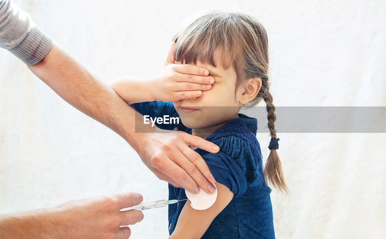 Hands giving vaccination to girl