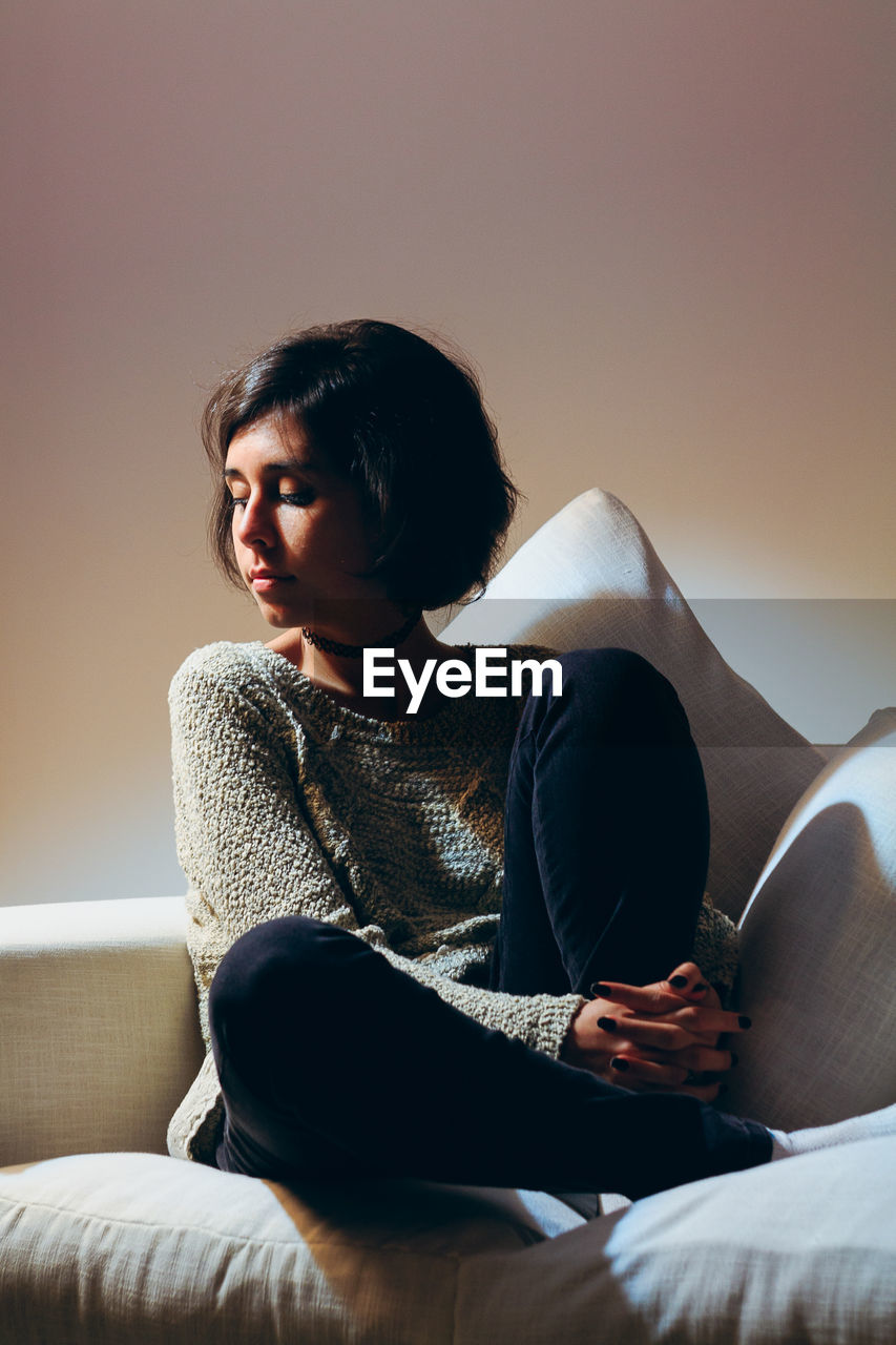 Young woman sitting on sofa at home