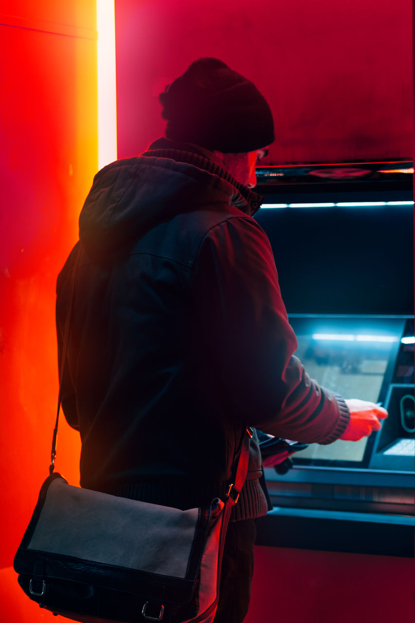 Man at the atm machine for withdrawing money in a cold winter night