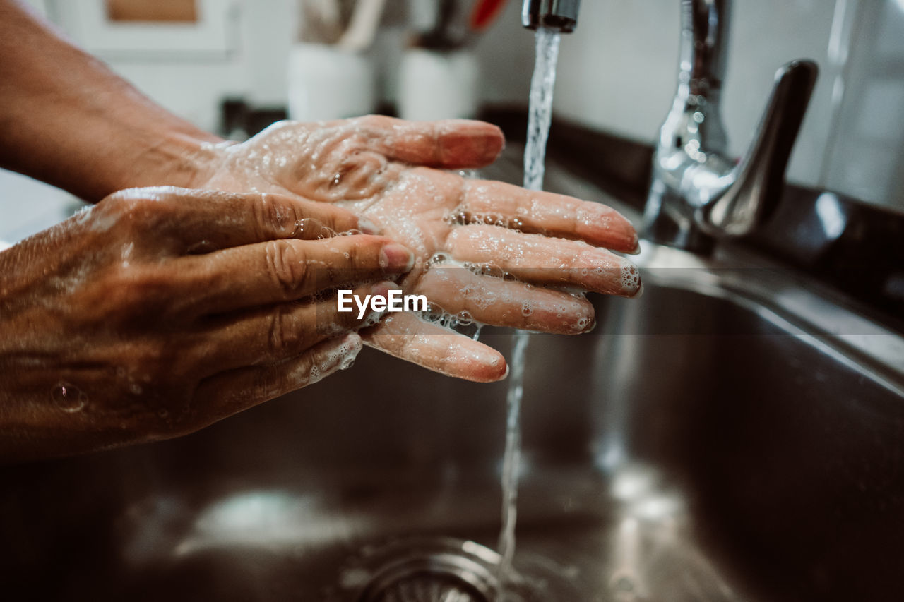 Cropped image of man washing hands in sink