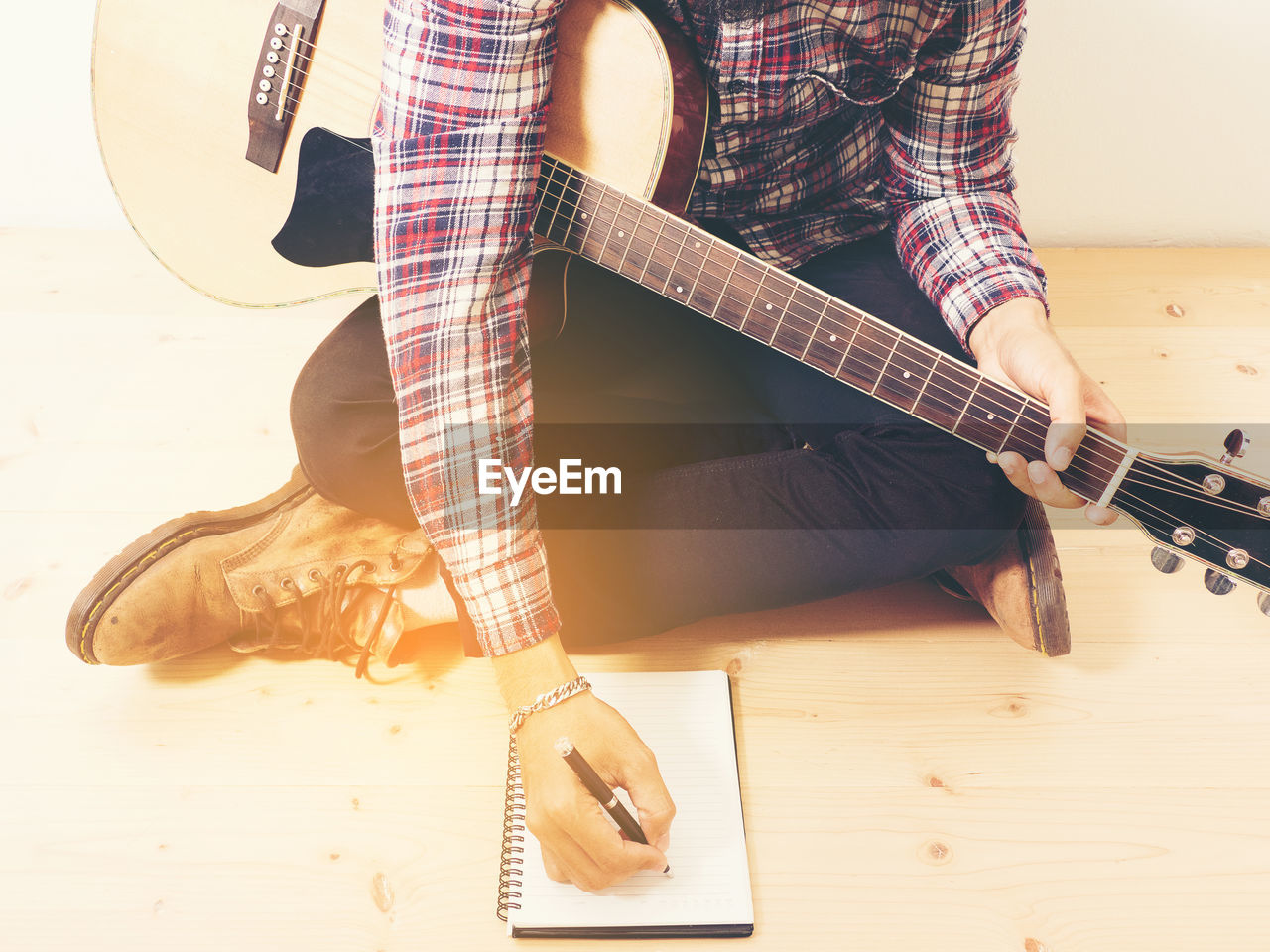 LOW SECTION OF MAN PLAYING GUITAR AT HOME