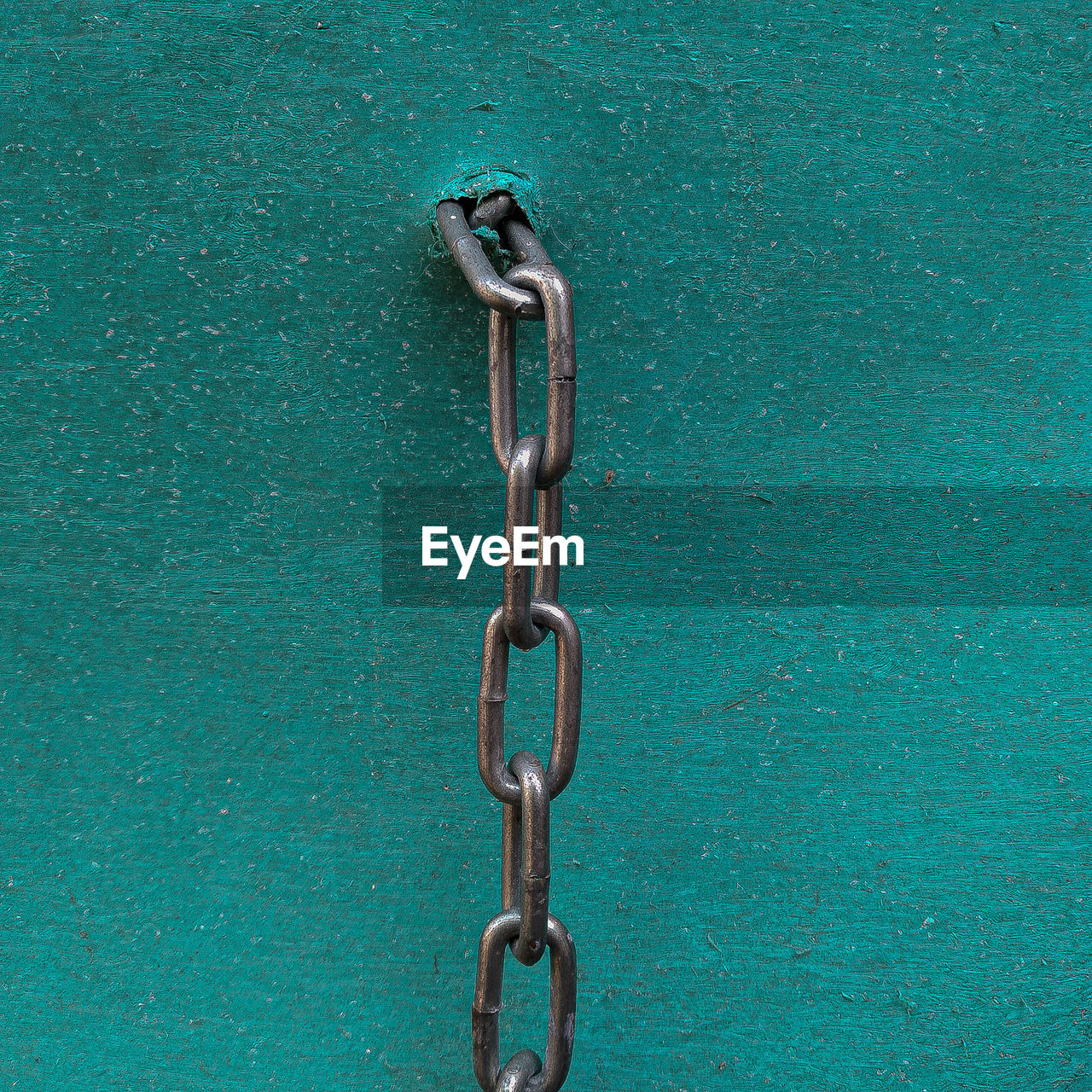 Close-up of chain hanging against blue wall