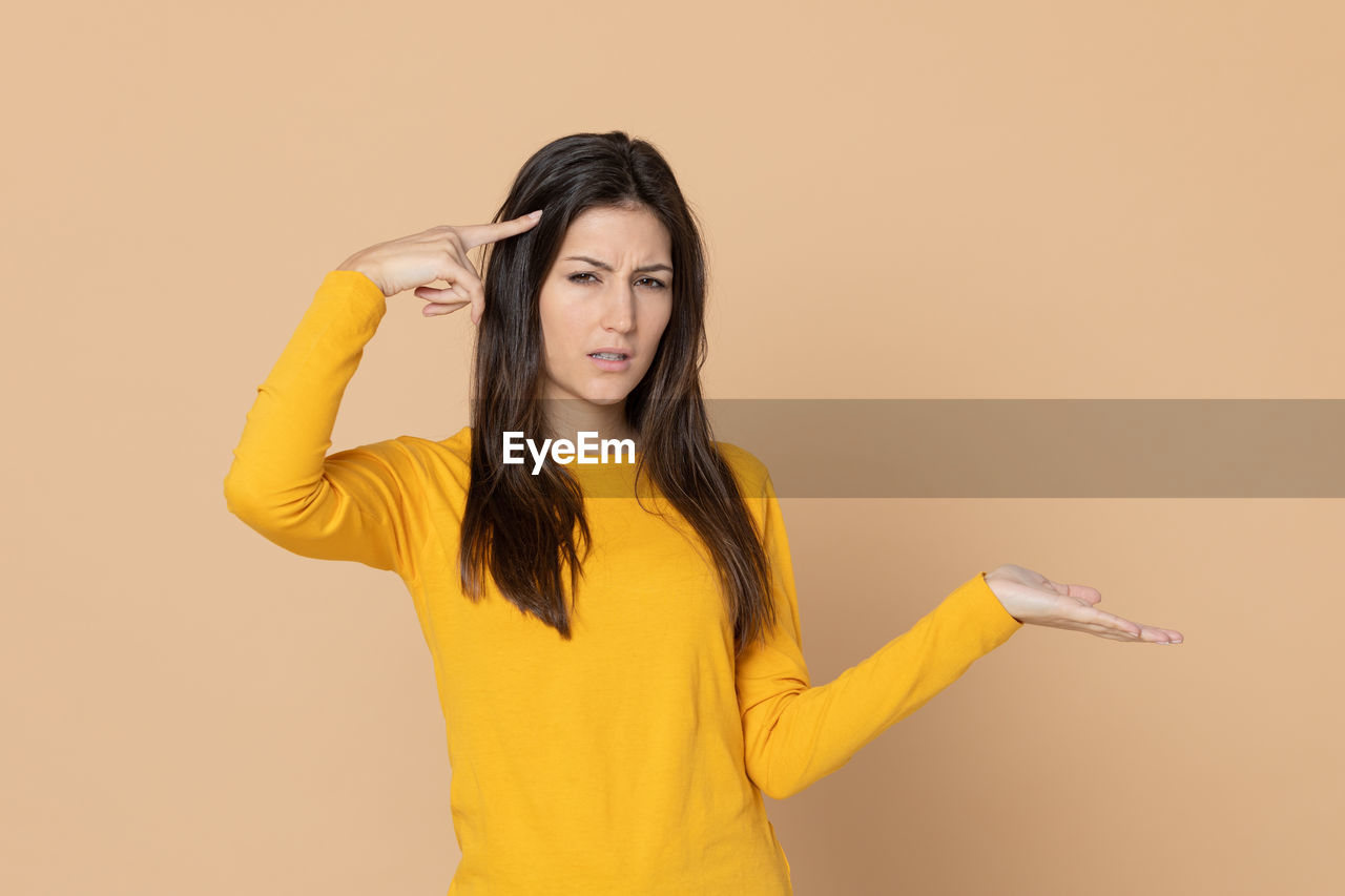 WOMAN STANDING AGAINST YELLOW BACKGROUND