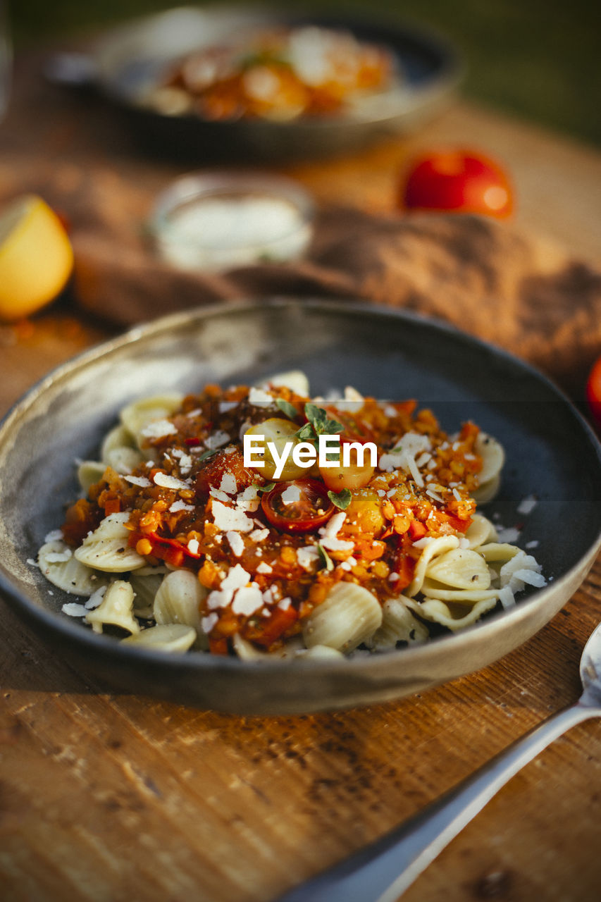Close-up of vegetarian lentil bolognese with orecchiette and mozzarella on table