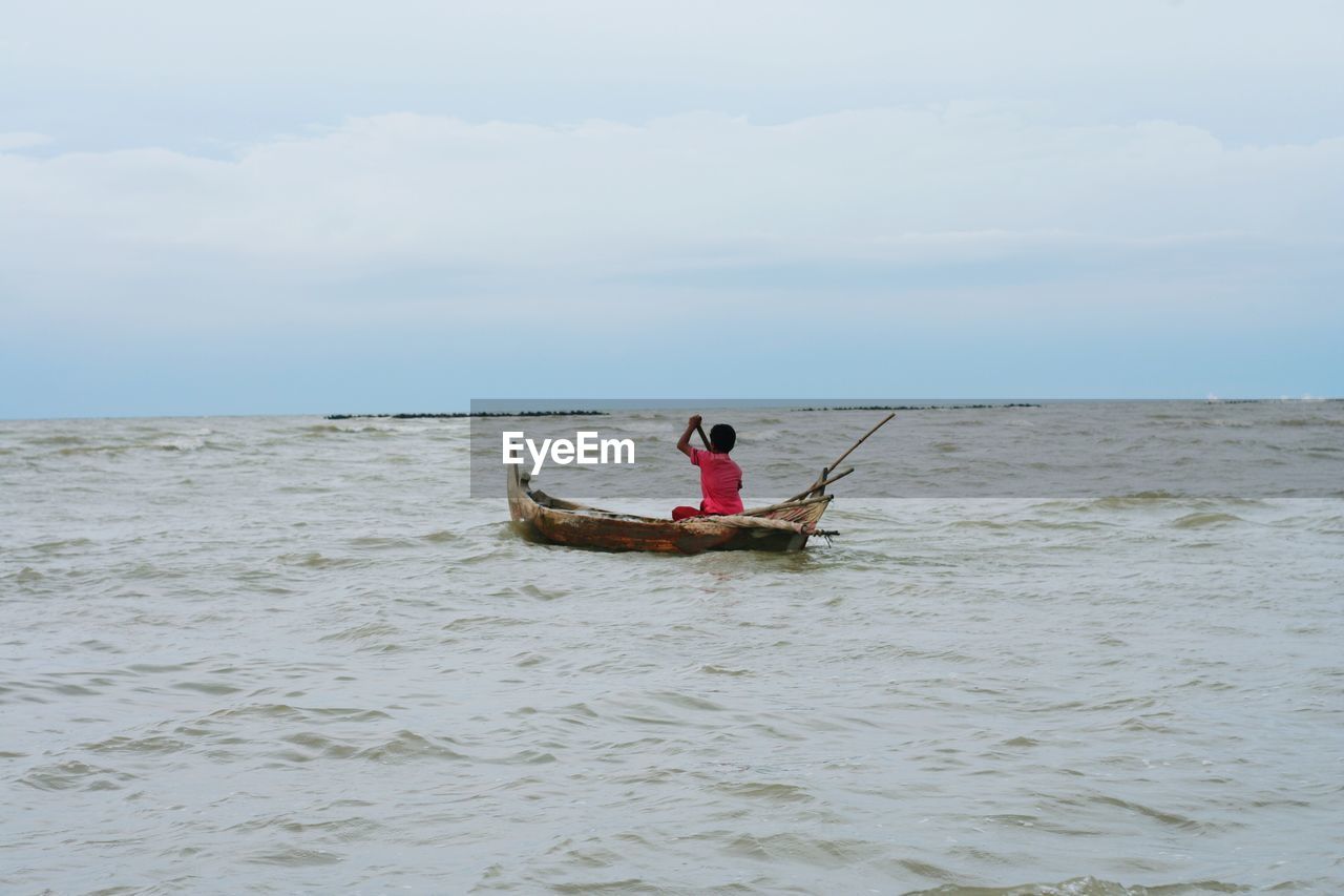 Man on boat in sea against sky