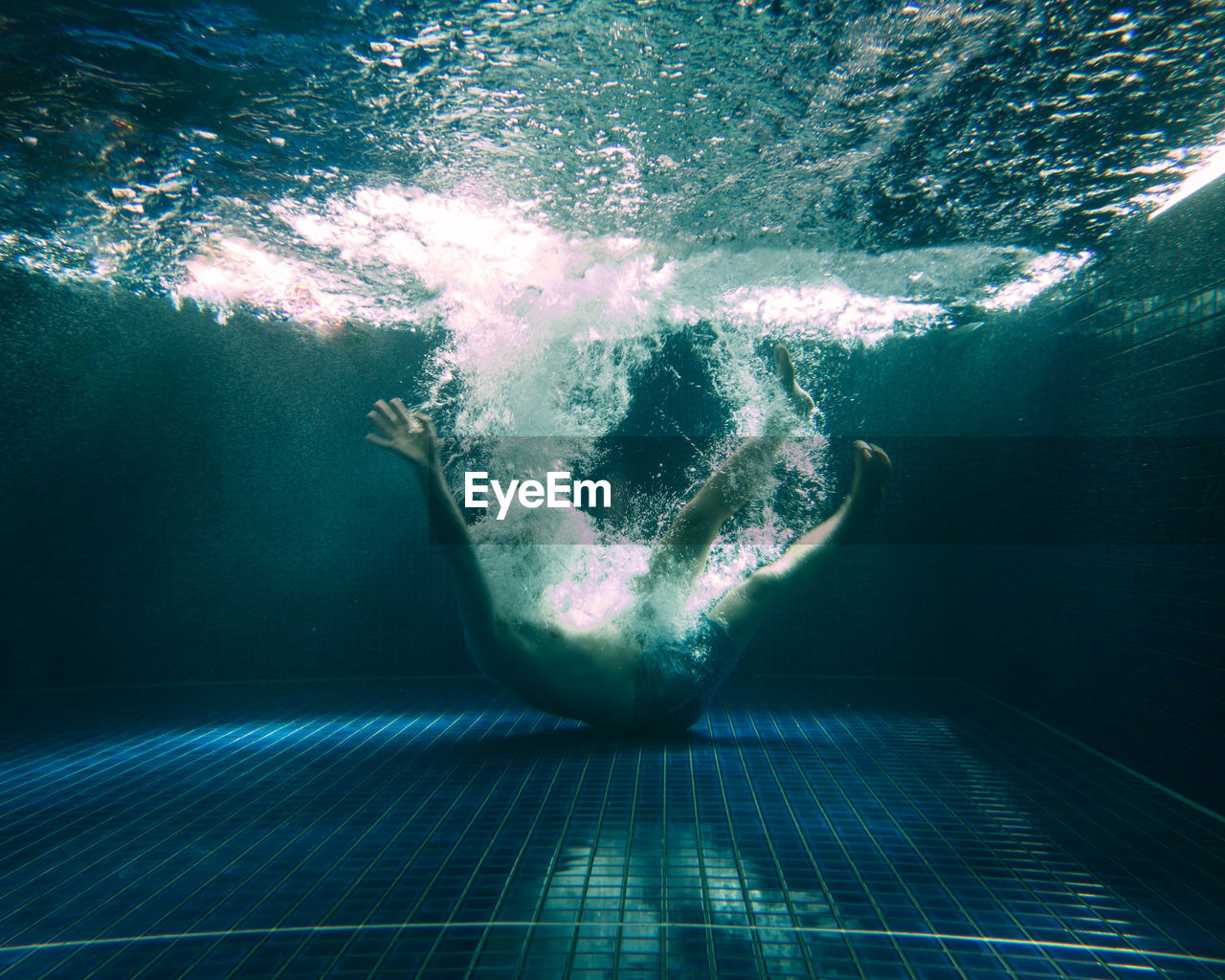 Man falling underwater in pool