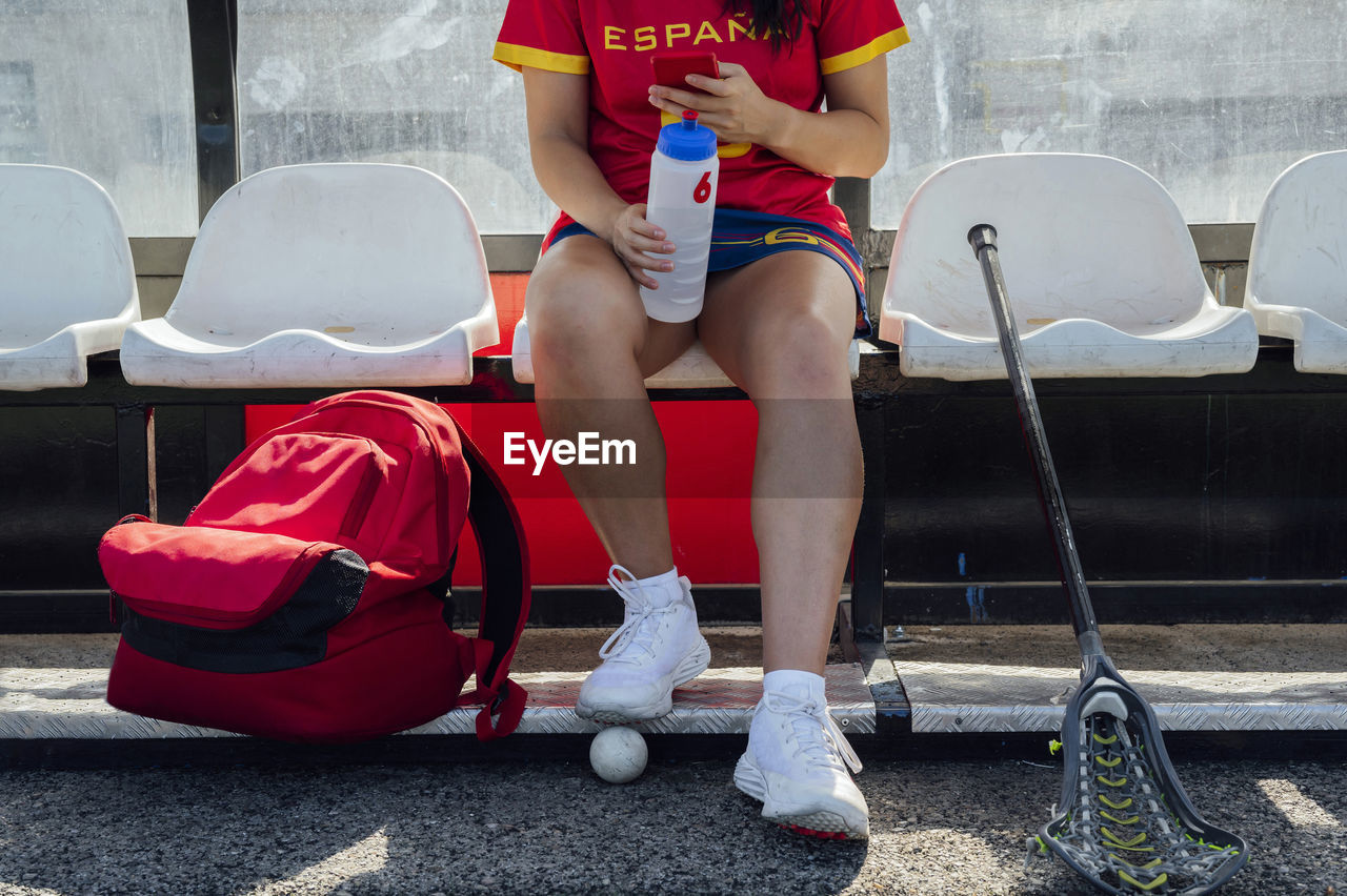 Player using smart phone sitting on seat at dugout