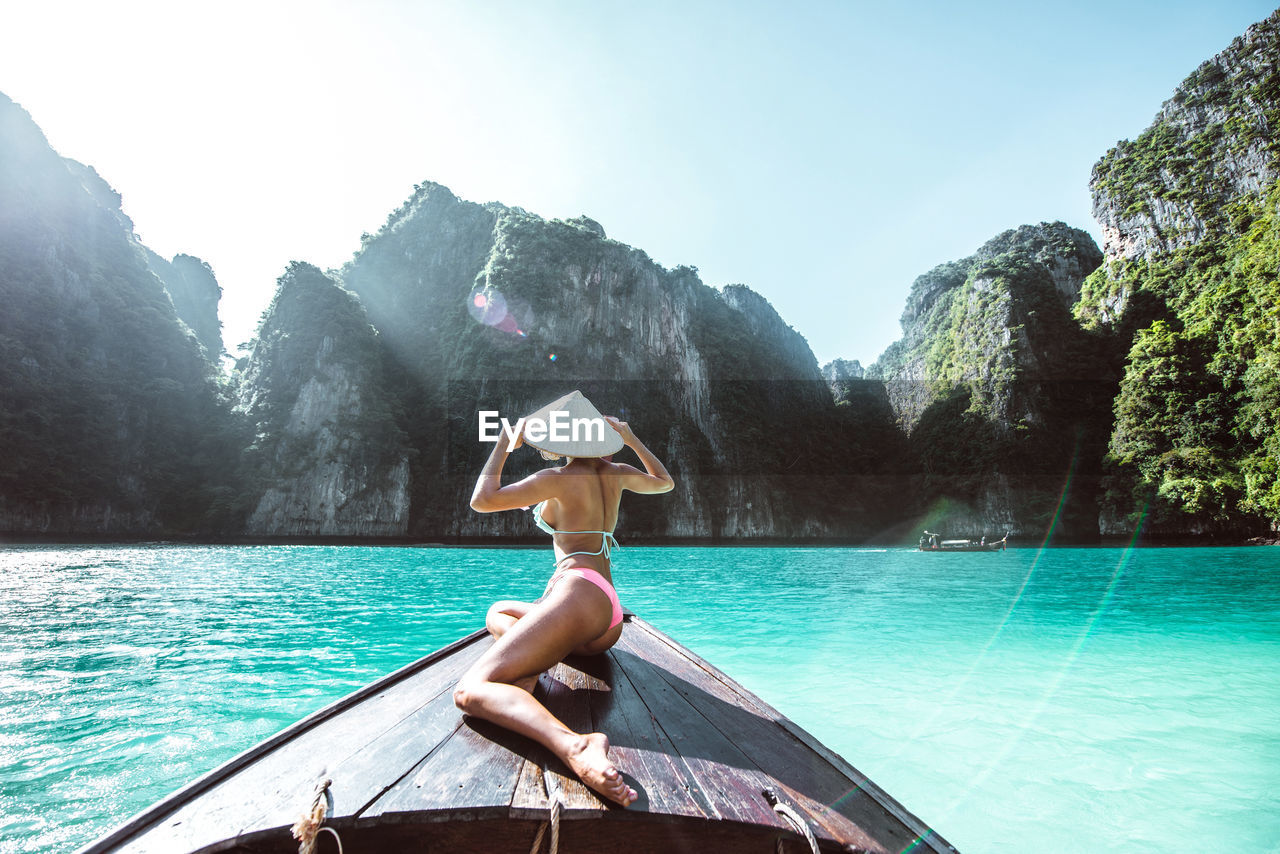 Rear view of woman wearing bikini in boat on sea