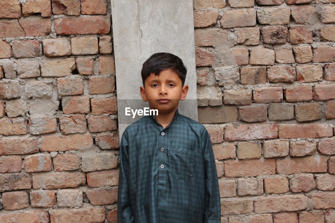 Portrait of child standing against brick wall