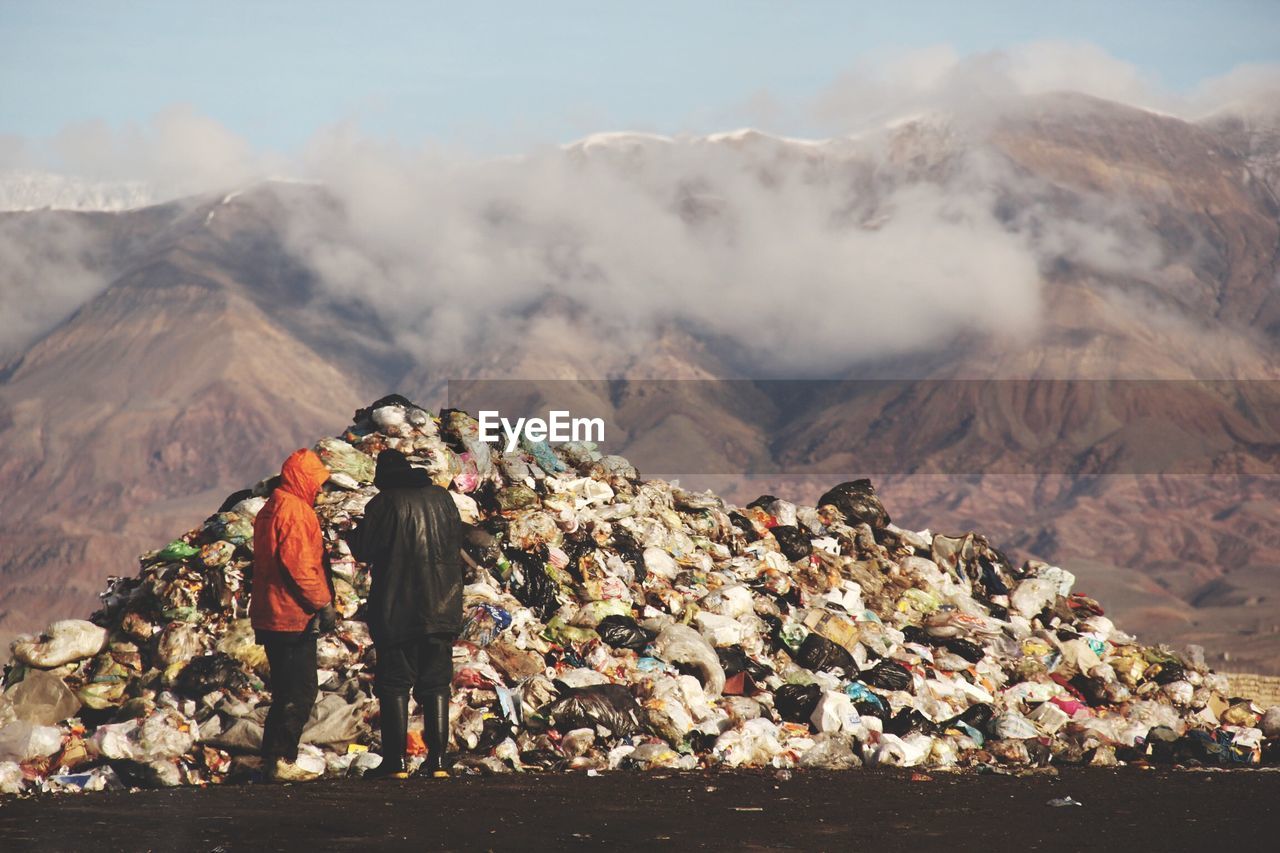 People standing in front of garbage against rocky mountains