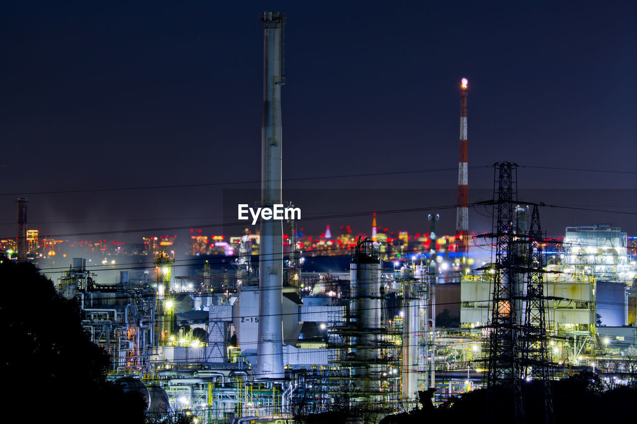 Illuminated factory against sky at night