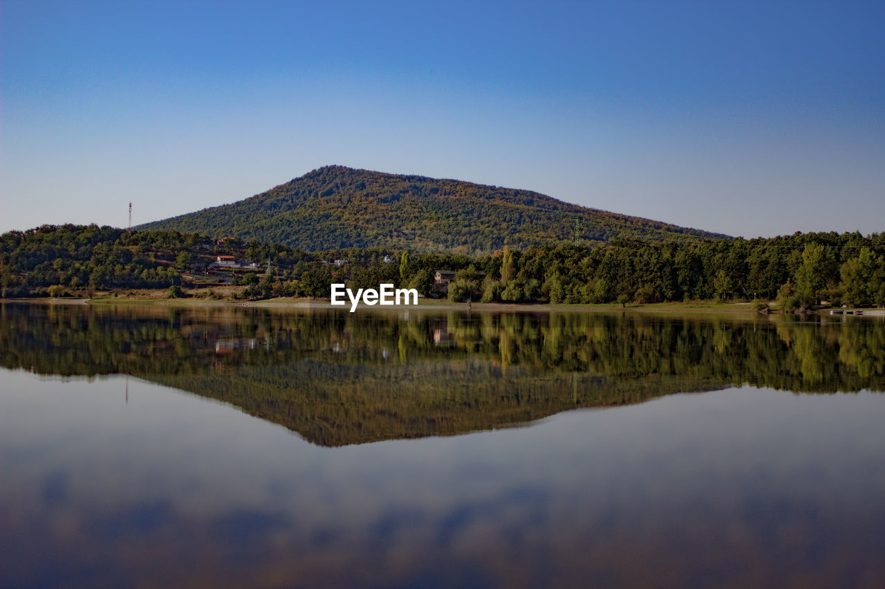 Scenic view of lake and mountains against clear blue sky