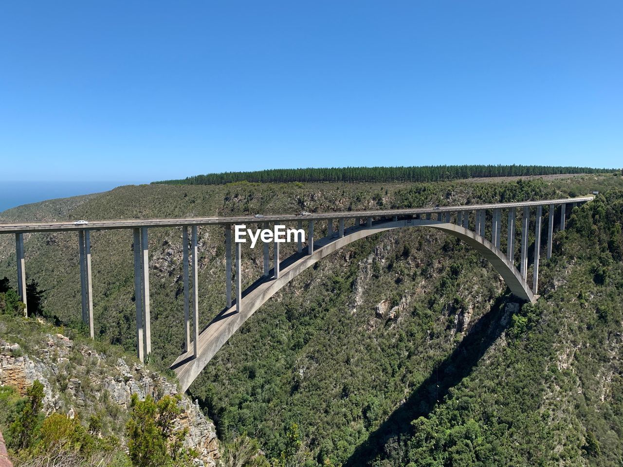 Arch bridge over land against clear blue sky