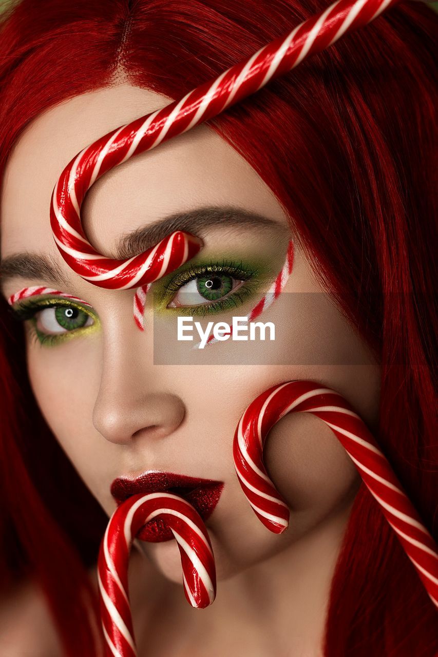 Close-up portrait of redhead woman with candy canes