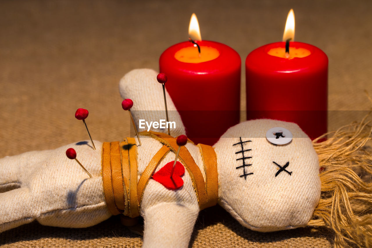 Close-up of spooky doll with illuminated candles