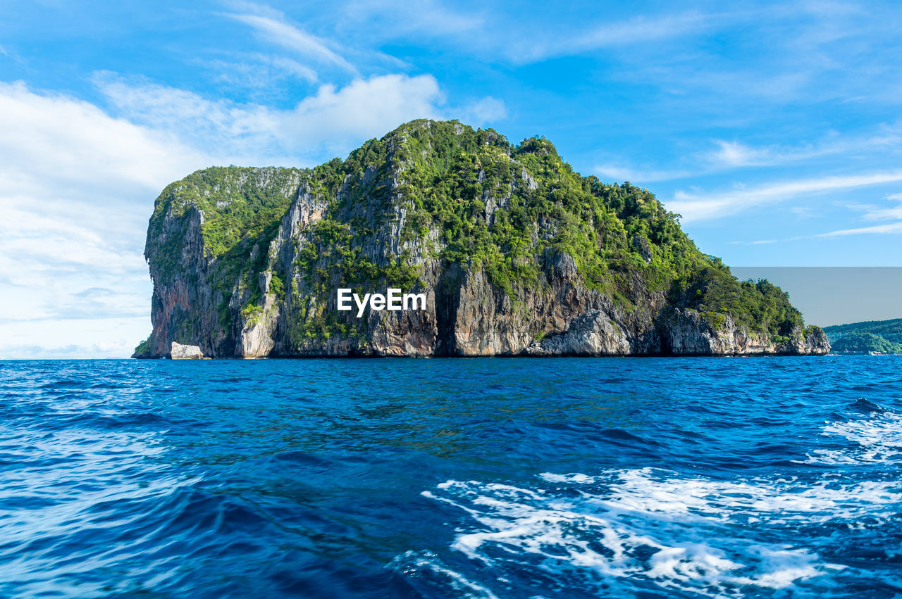 Scenic view of rocky mountain in sea against blue sky at ko phi phi le