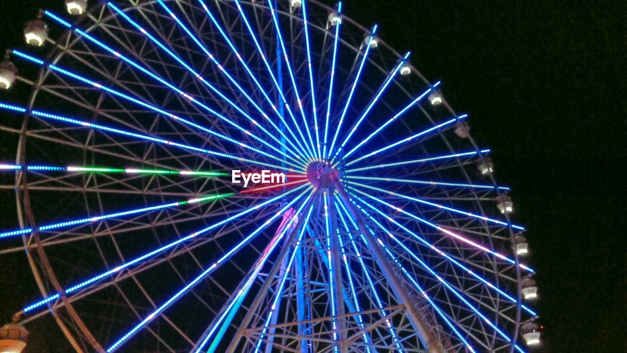 Low angle view of illuminated ferris wheel at sky fun