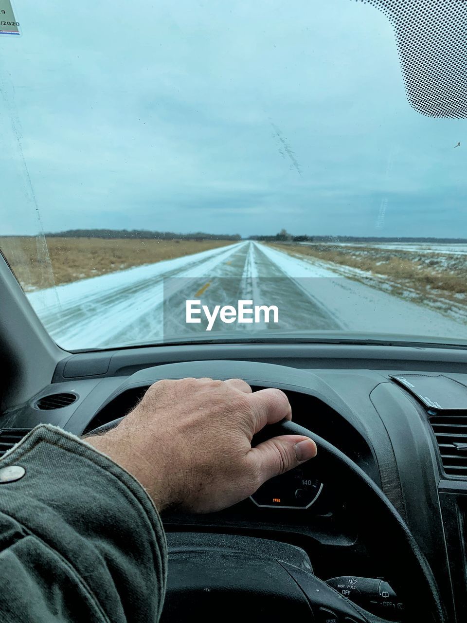 Cropped image of man driving car on road against sky 