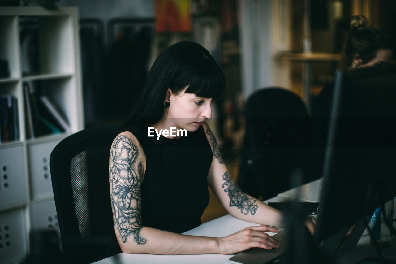 Tattooed woman working at desk in office
