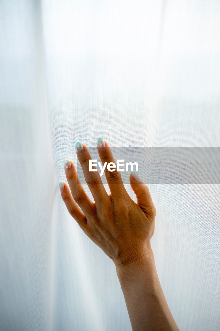 Cropped hand of woman on window