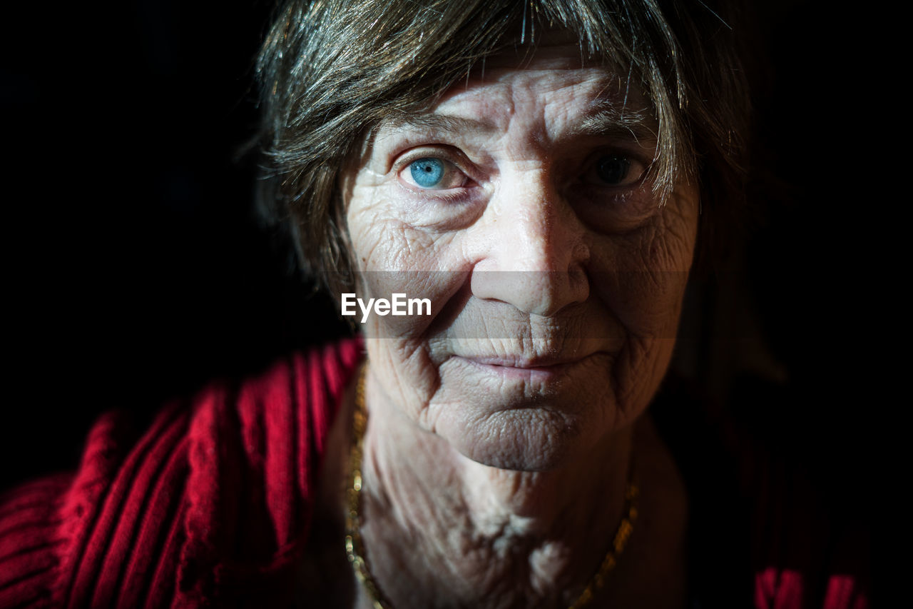 Close-up portrait of senior woman against black background