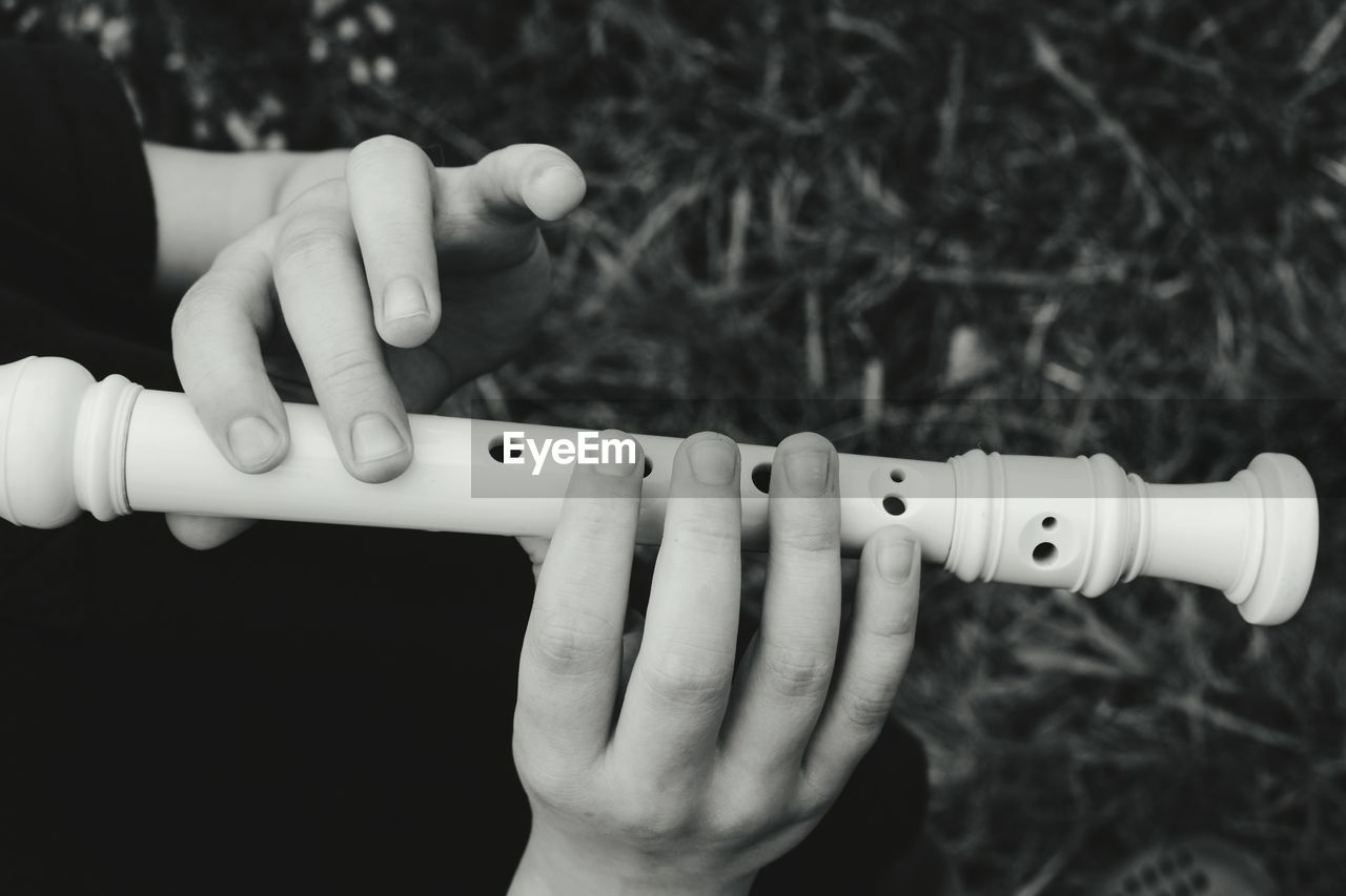 Cropped hands of person playing flute