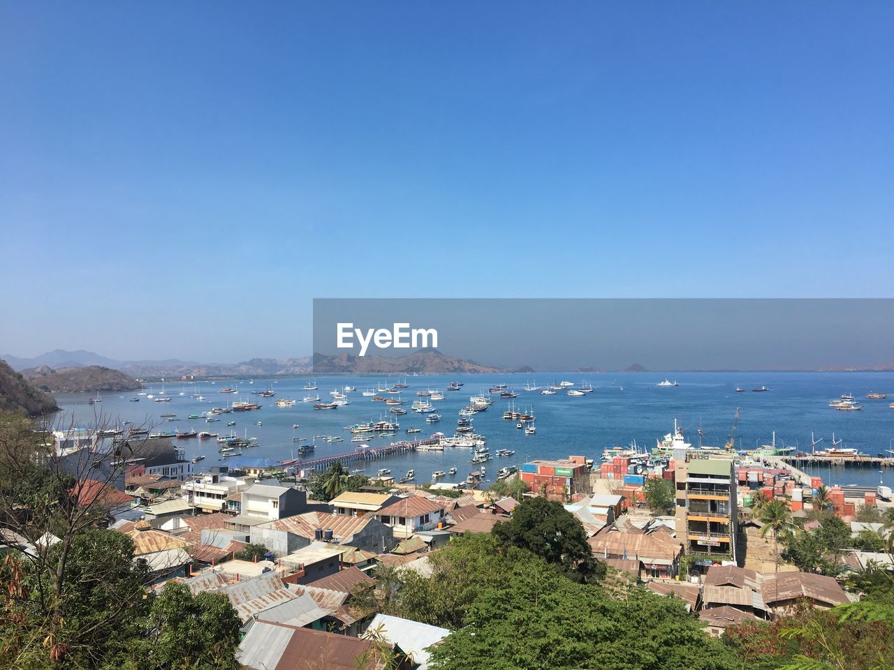 High angle view of townscape by sea against blue sky