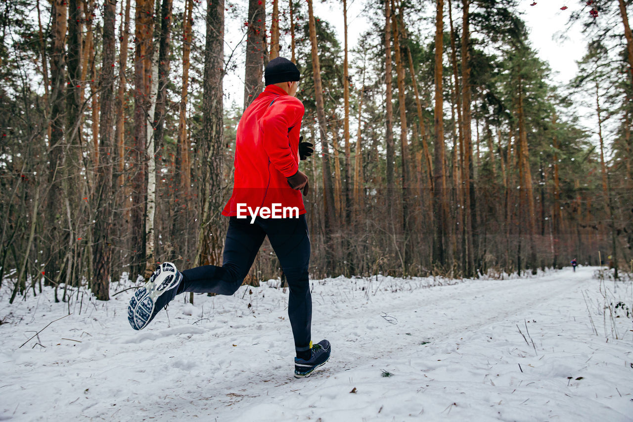 Male runner running winter race in forest