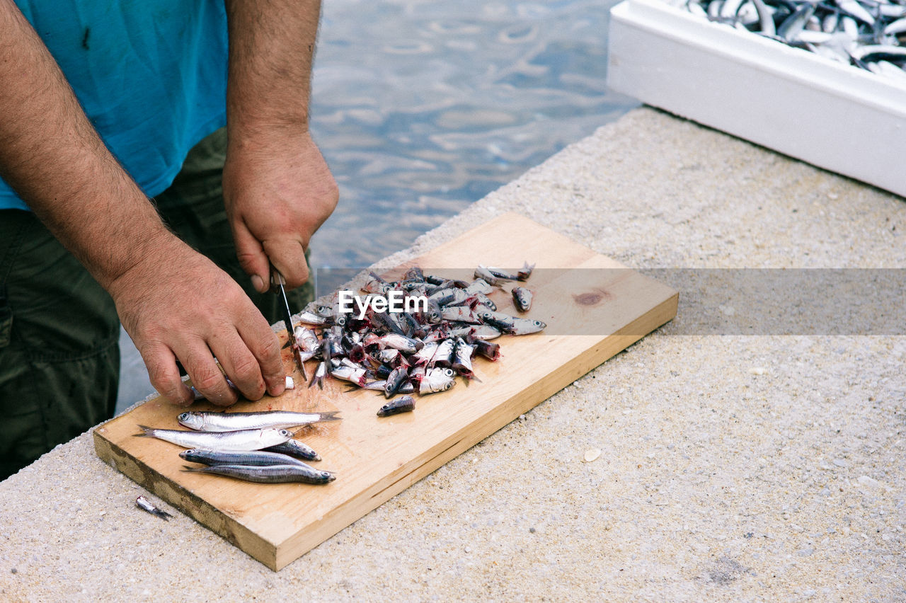 Midsection of man cutting fish on board