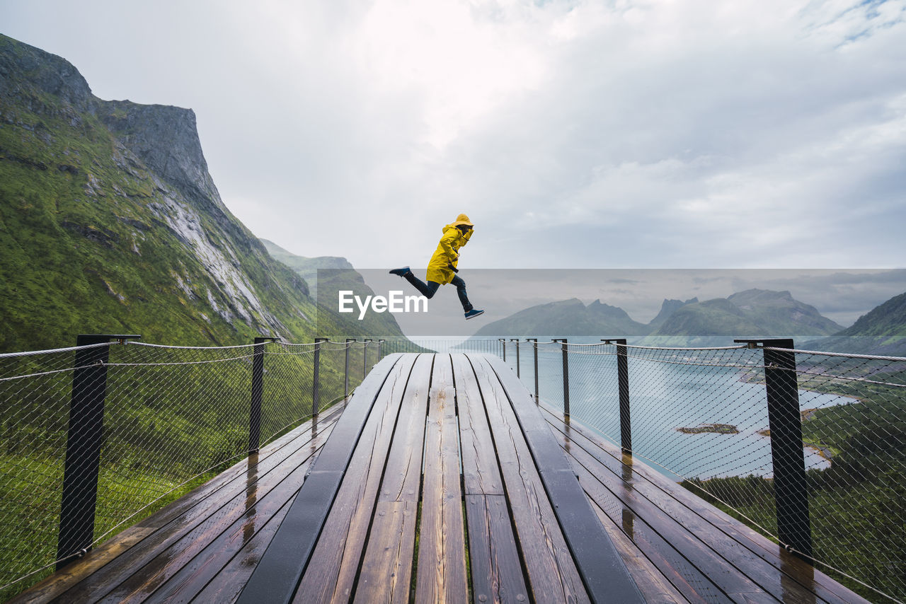 Norway, senja island, man jumping on an observation deck at the coast