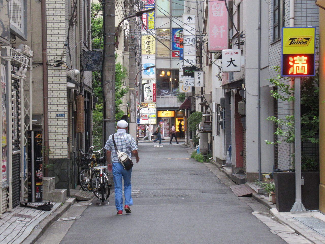 FULL LENGTH REAR VIEW OF MAN WALKING ON STREET AMIDST BUILDINGS