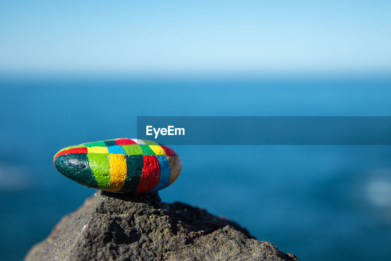 Close-up of multi colored pebble on rock against sea