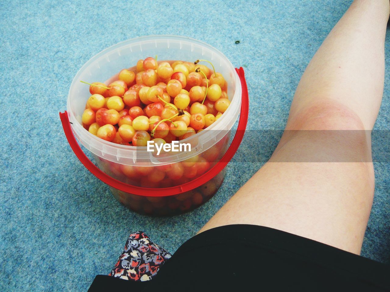 Cropped image of woman sitting by basket with fruits