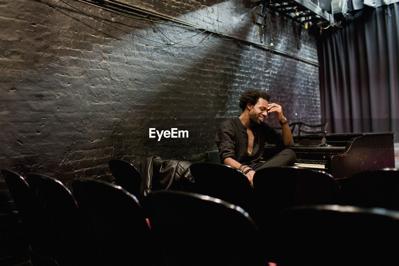 Musician sitting at a piano in a small theater