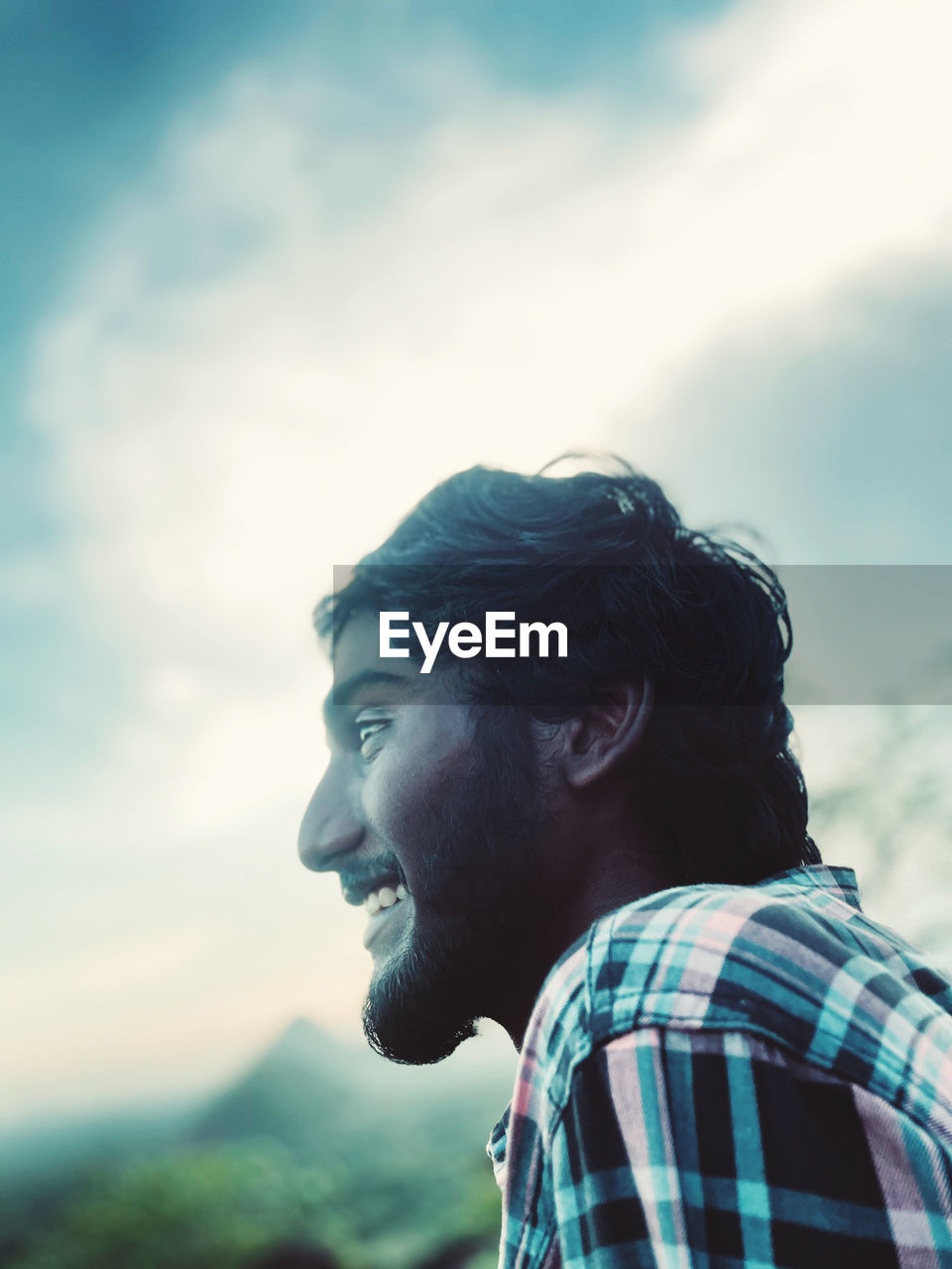 Portrait of young man looking away against sky