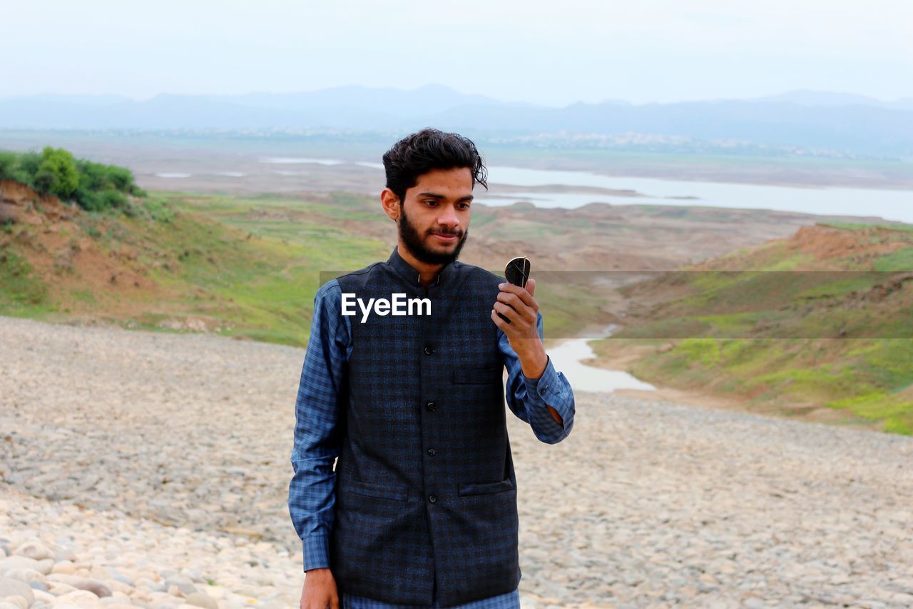 Young man standing against mountain
