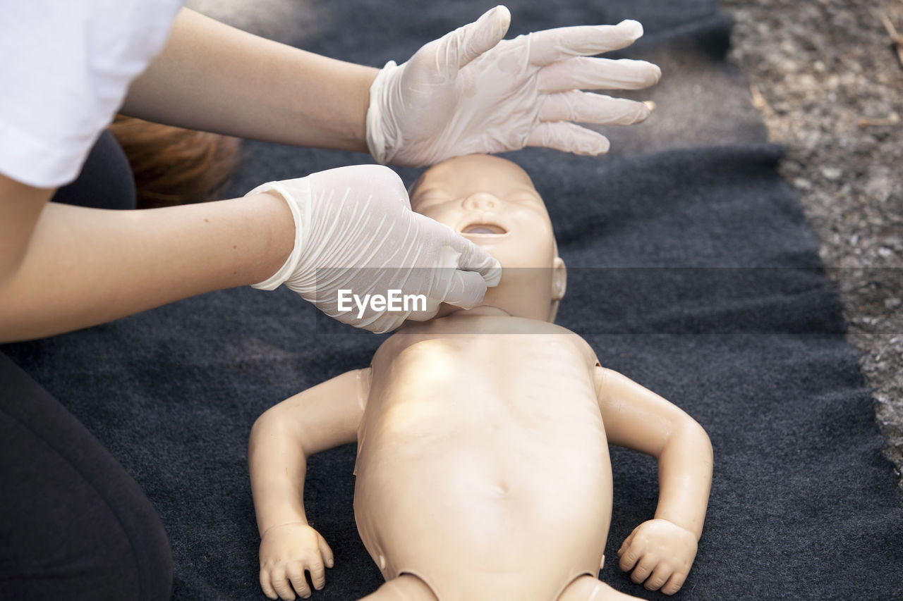 Cropped image of paramedics performing cpr on baby mannequin