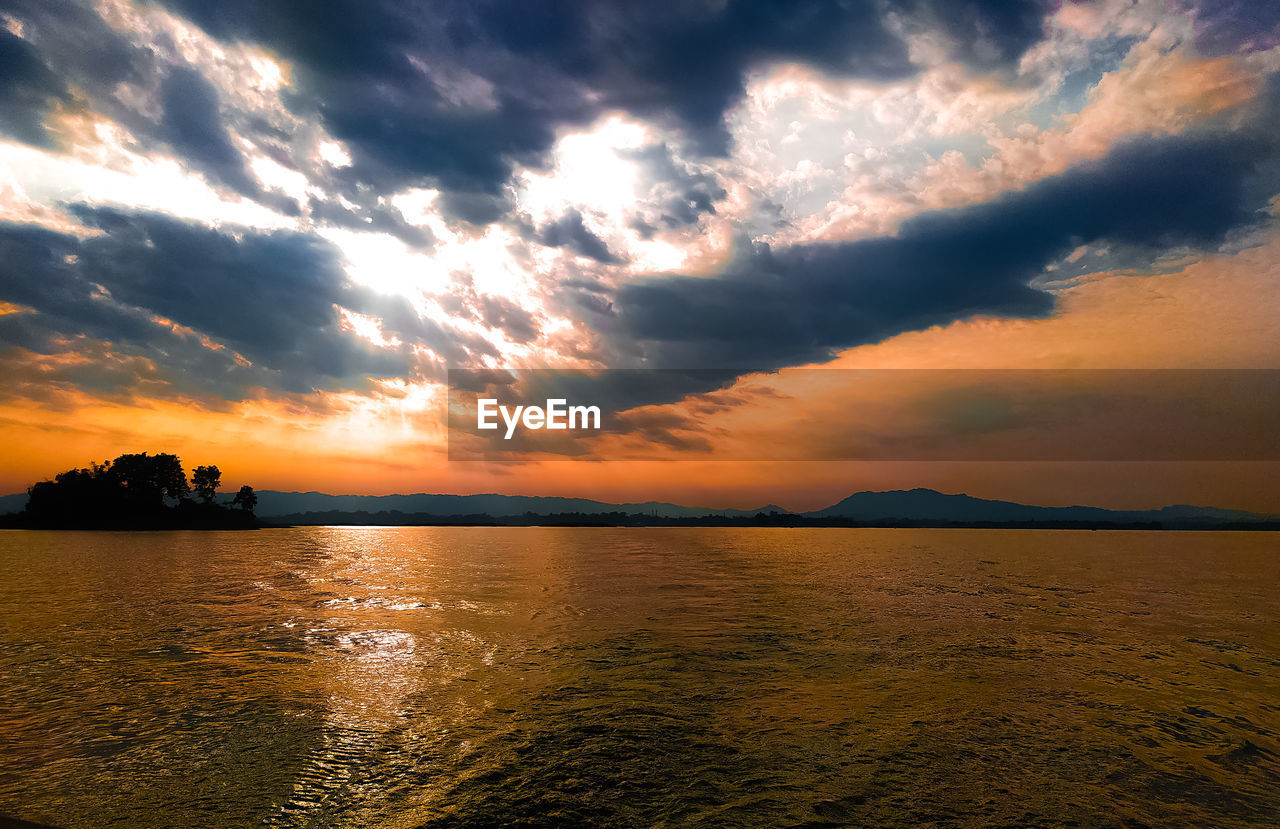 Scenic view of sea against dramatic sky during sunset