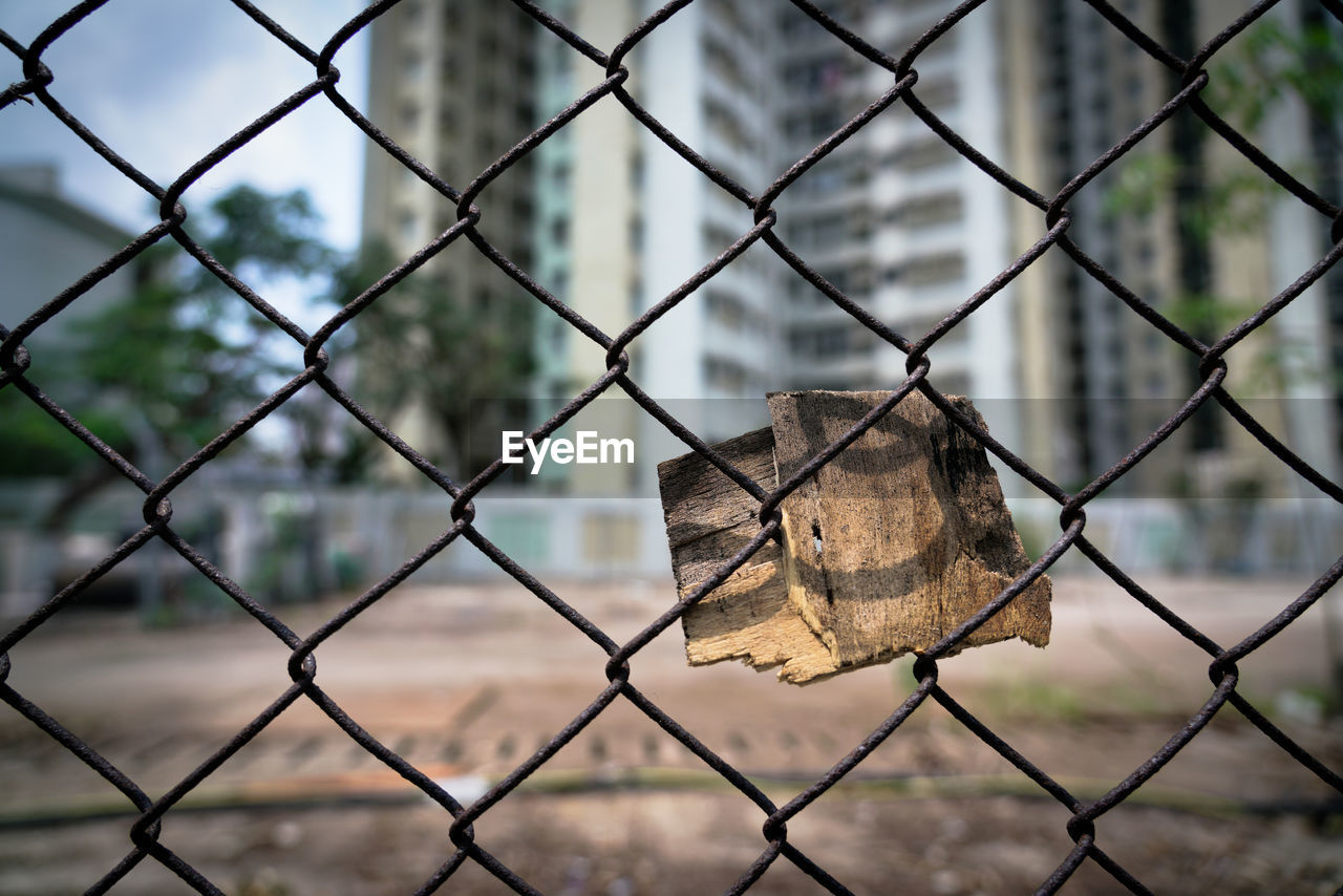 CLOSE-UP OF PADLOCK ON CHAINLINK FENCE AGAINST BLURRED BACKGROUND