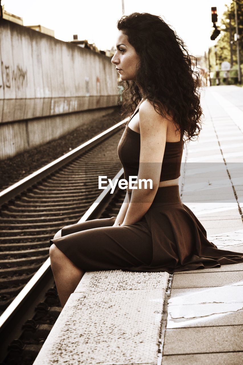Side view of woman sitting on railroad station platform