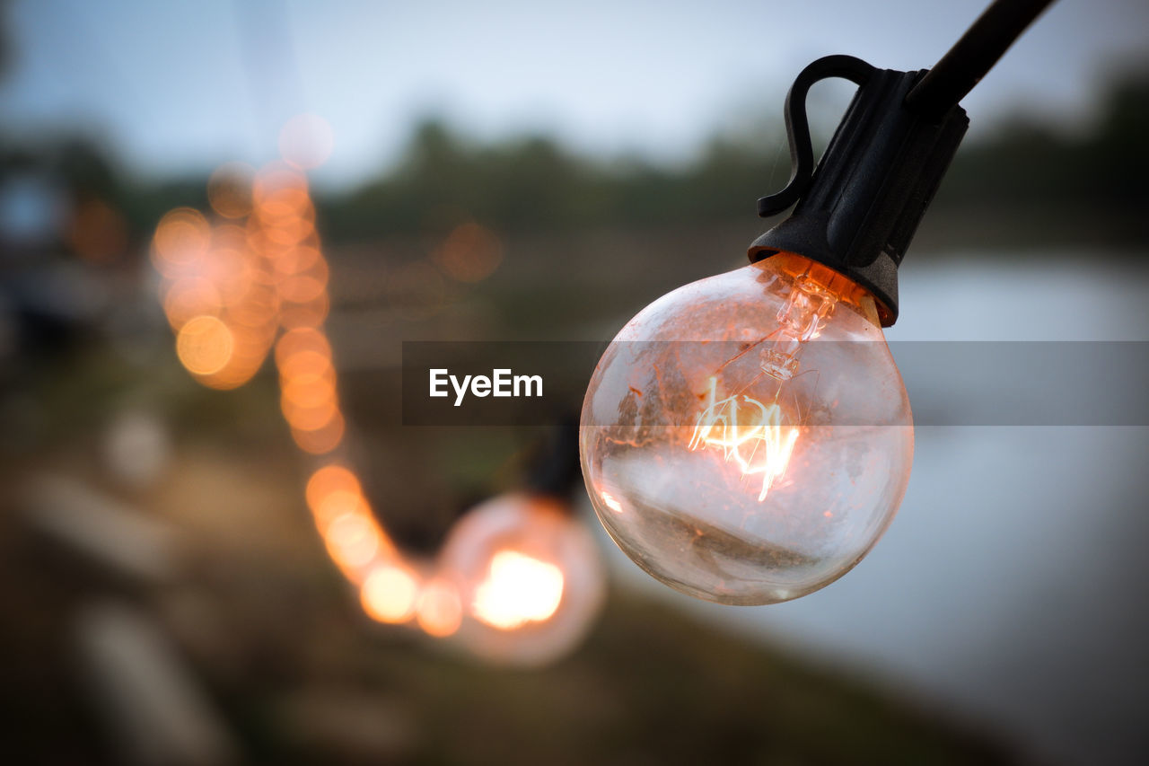 CLOSE-UP OF LIGHT BULB HANGING ON GLASS