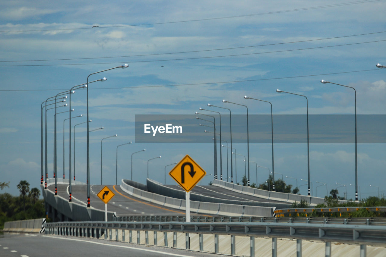 Road sign on bridge against sky