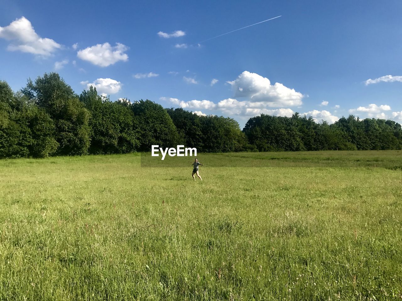 Young woman on grassy field against sky