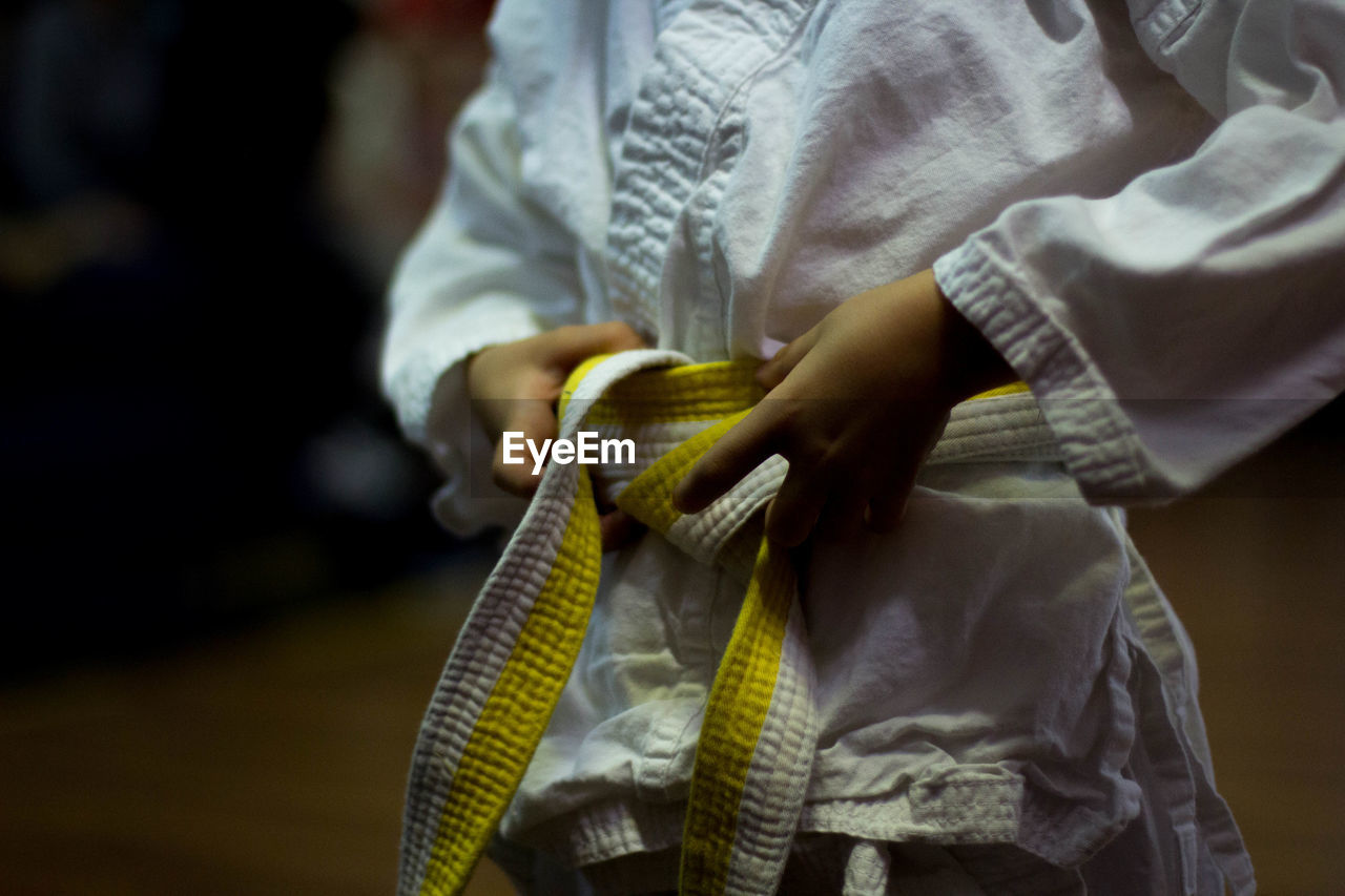 Midsection view of person tying karate belt