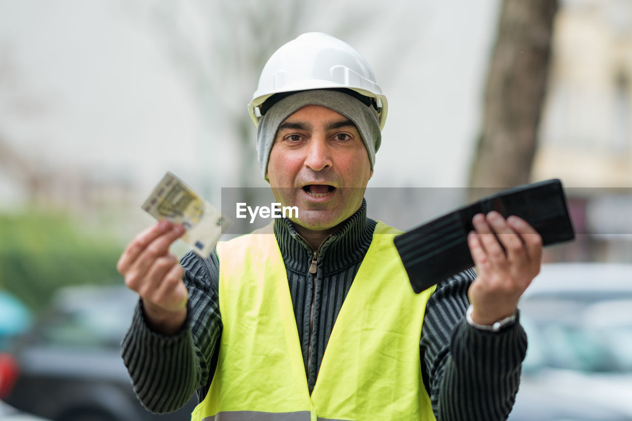 Portrait of engineer in reflective clothing holding currency and wallet