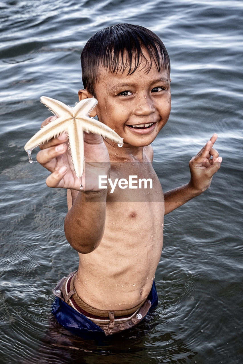 PORTRAIT OF HAPPY BOY HOLDING SEA