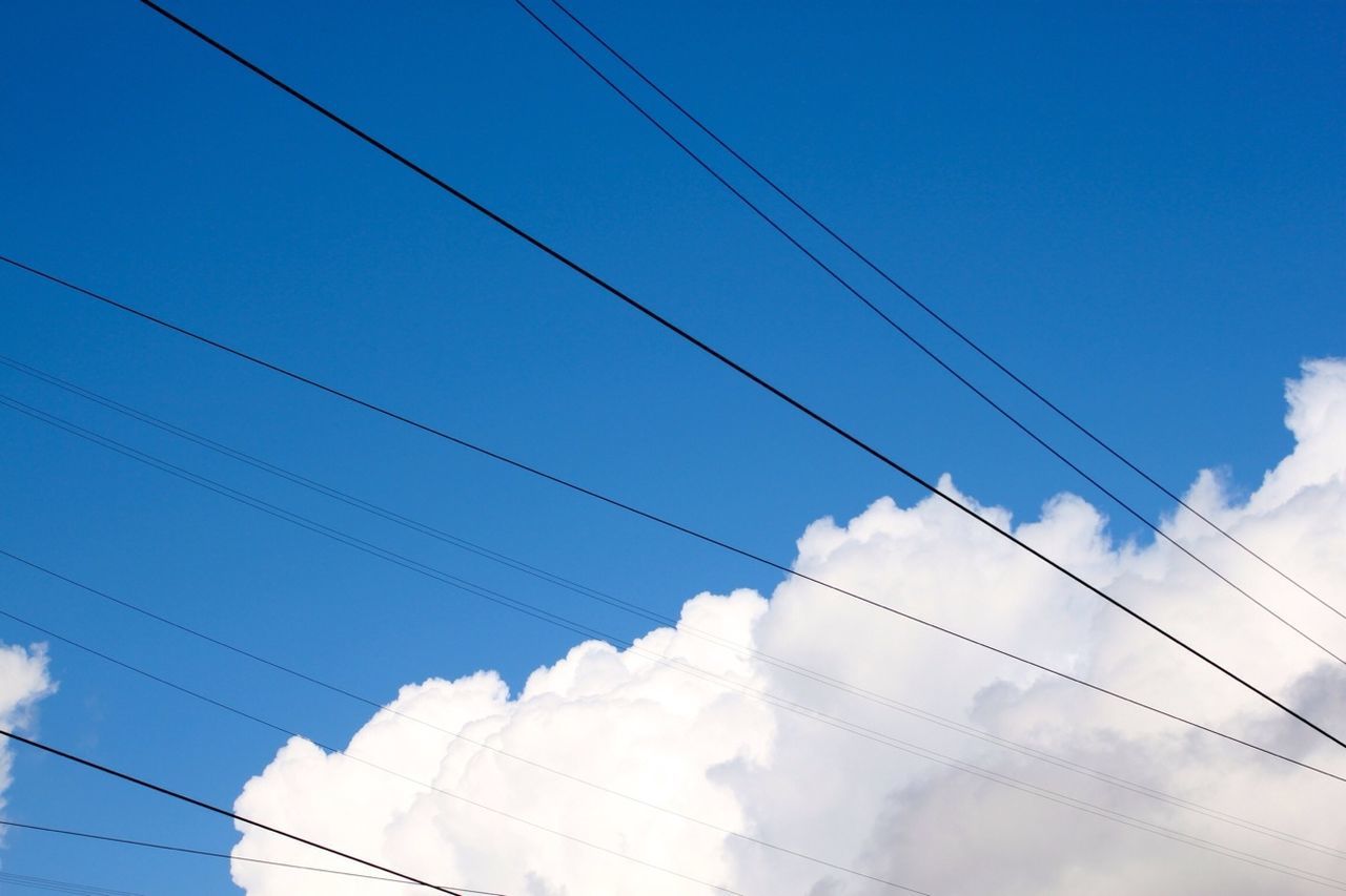 Low angle view of electricity cables against cloudy sky