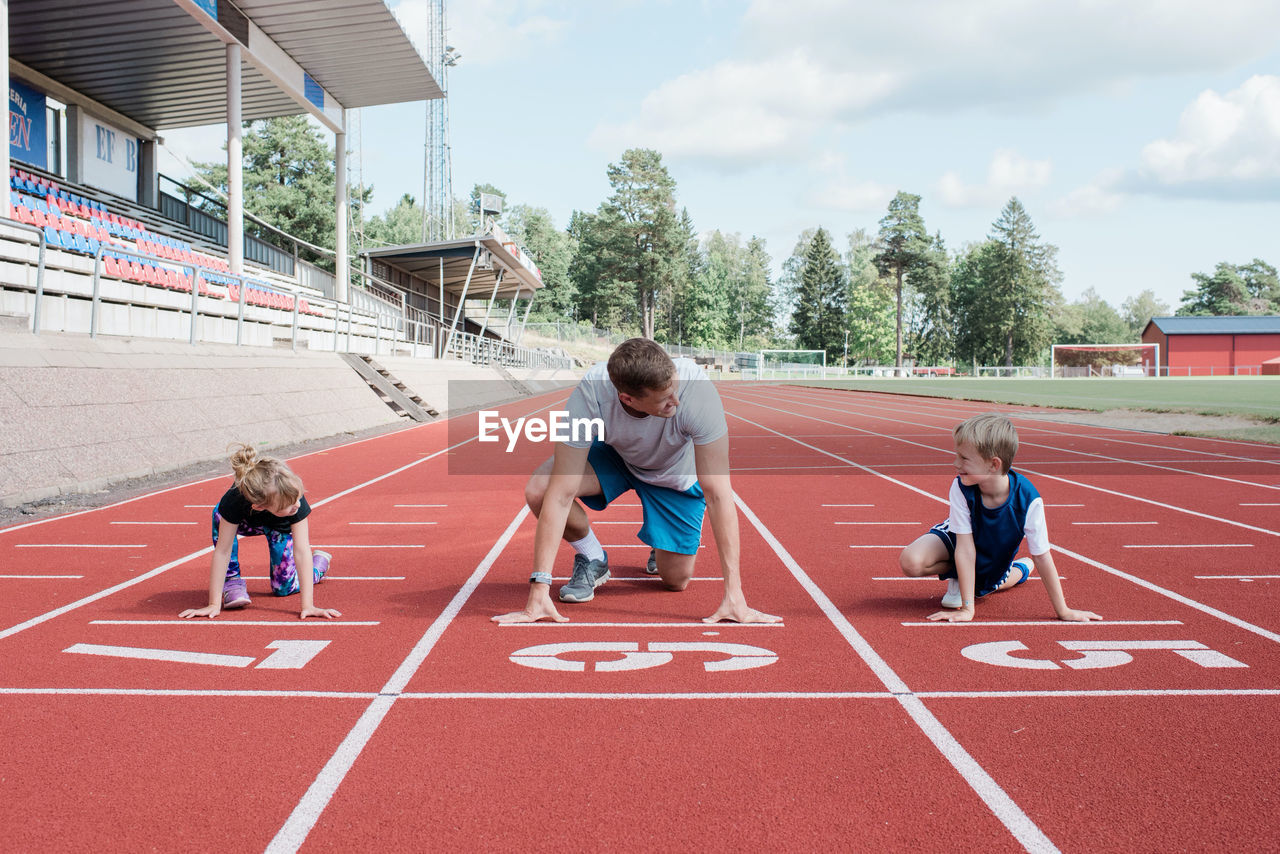 Father and his kids getting ready to run on a track to race
