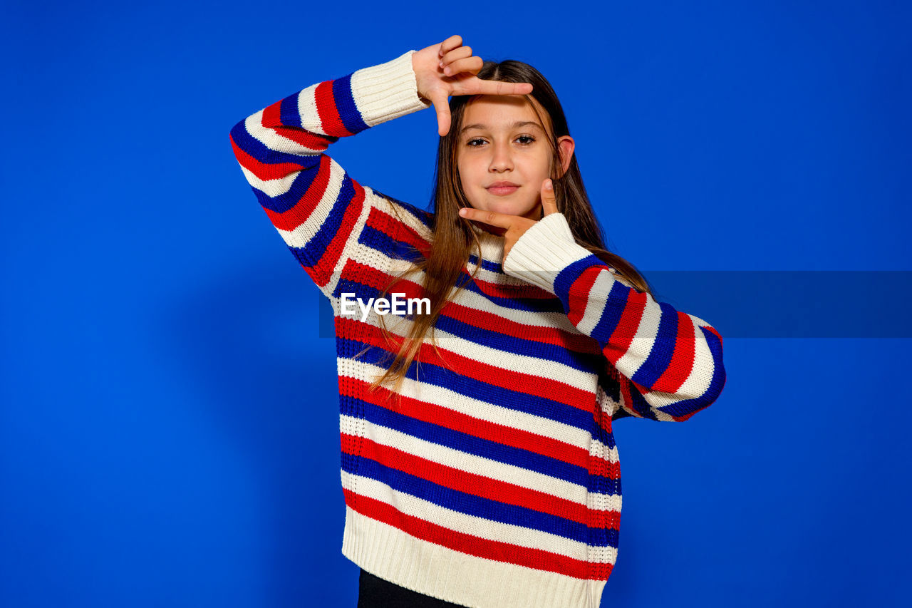 one person, blue, striped, studio shot, colored background, portrait, adult, clothing, blue background, young adult, waist up, women, emotion, standing, copy space, casual clothing, looking at camera, arm, front view, indoors, hand, arms raised, looking, person, child, sports, human limb, limb