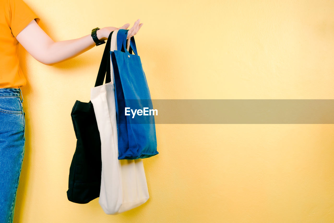 Asian woman shopping by use fabric bag instead of plastic bag with yellow pastel background